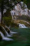 Waterfalls cascading down a mountainside over mossy green rocks in a tranquil scene of great natural beauty