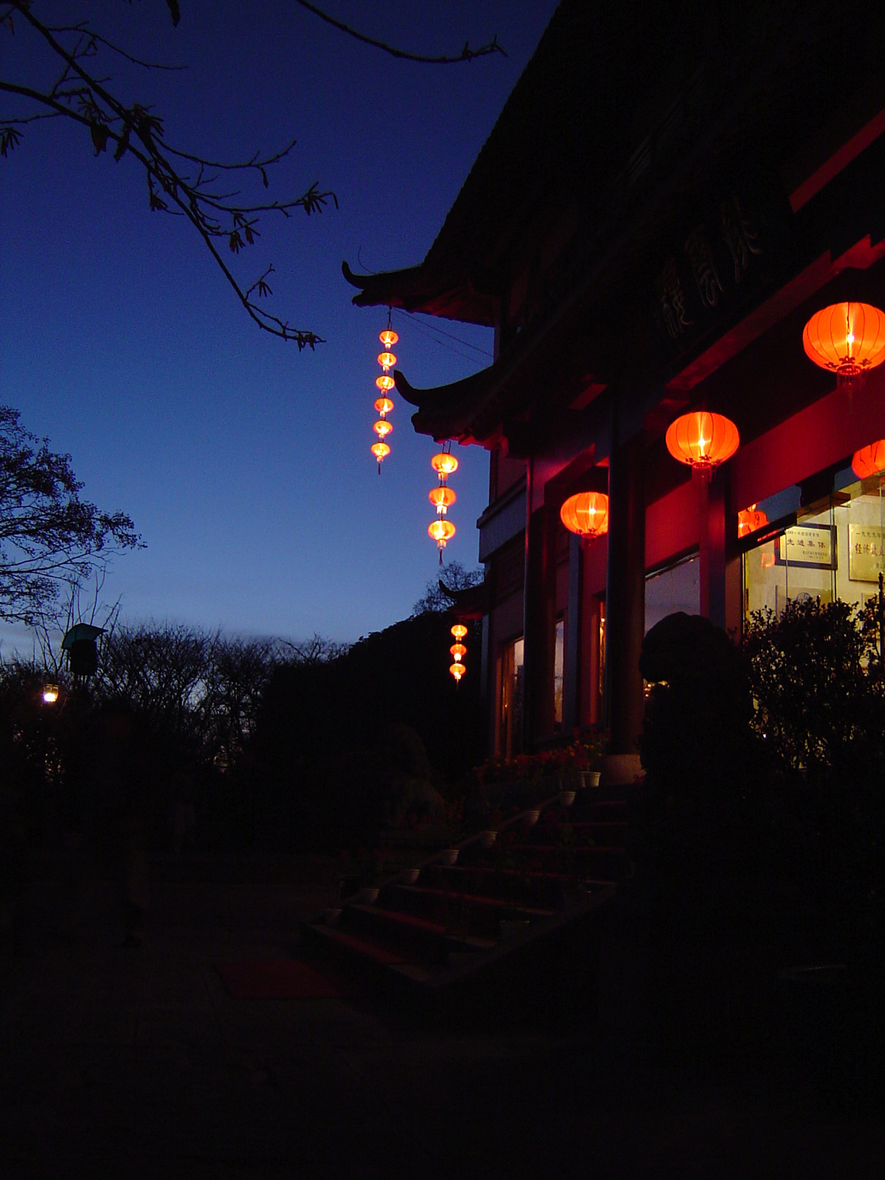an image of Night scene of a traditional Chinese house with colorful lighted lanterns hung at the entrance as a welcome to visitors