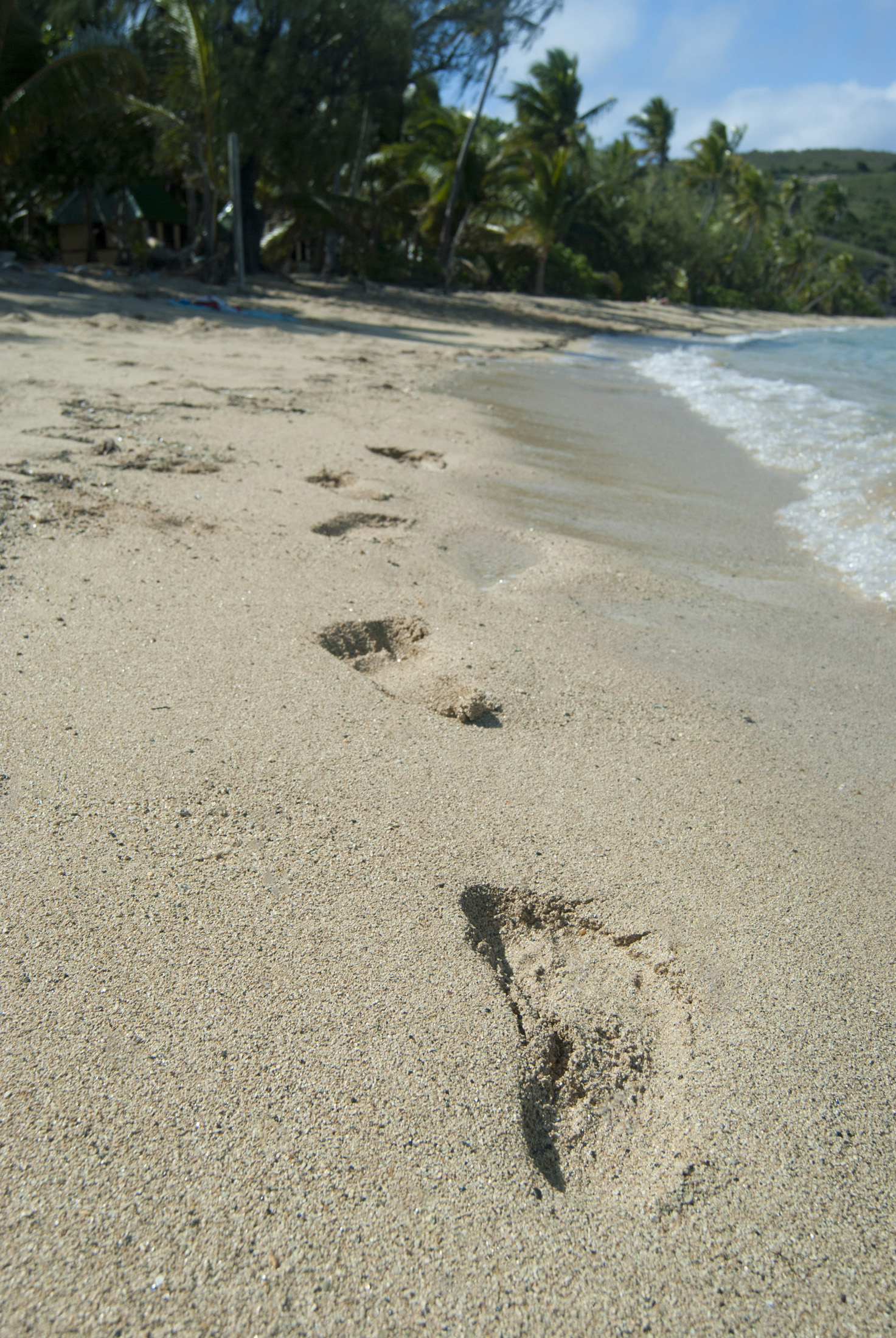 an image of Footprints on a tropical beach leading away along the line of surf with nobody in sight