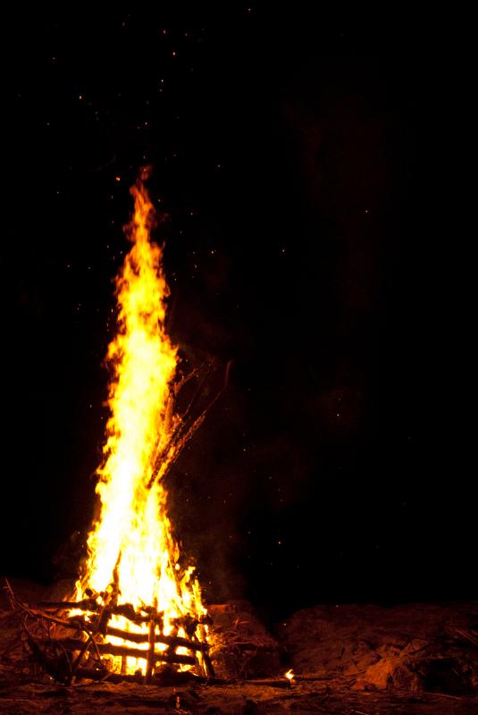 Blazing camp fire with flames leaping into the night sky and copyspace for your text