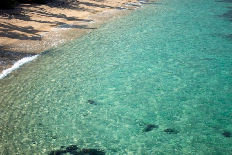 High angle view of a secluded peaceful sandy beach and bay with a beautiful clear sparkling tropical sea