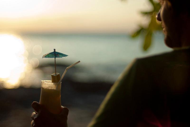 Man relaxing overlooking the ocean with a cocktail in his hand watching the tropical sunset
