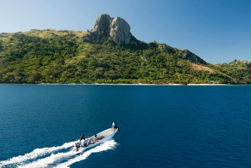 Open motorboat with tourists approaching the coast of Waya island, Fiji, a popular tourist destination