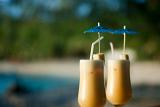 Tropical cocktails for two served in tall glasses with straws alongside the seashore, shallow dof and copyspace