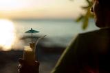 Man relaxing overlooking the ocean with a cocktail in his hand watching the tropical sunset