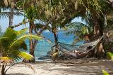 Relaxing in a hammock slung between two palm trees overlooking an idyllic tropical beach and ocean
