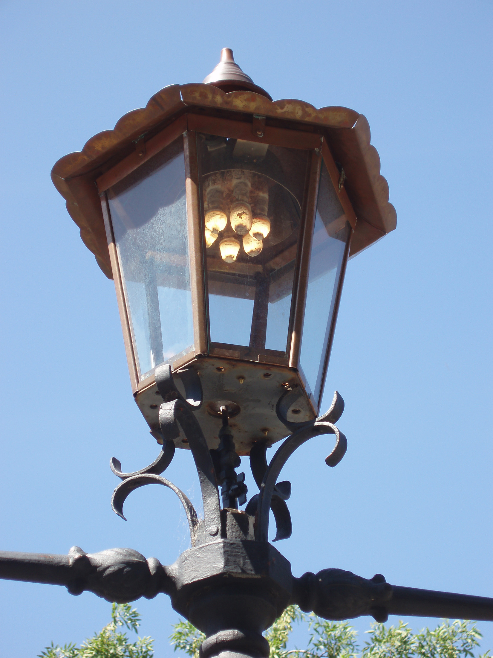 an image of Close up Vintage Style Gas Powered Street Lamp in Melbourne on Light Blue Sky Background.