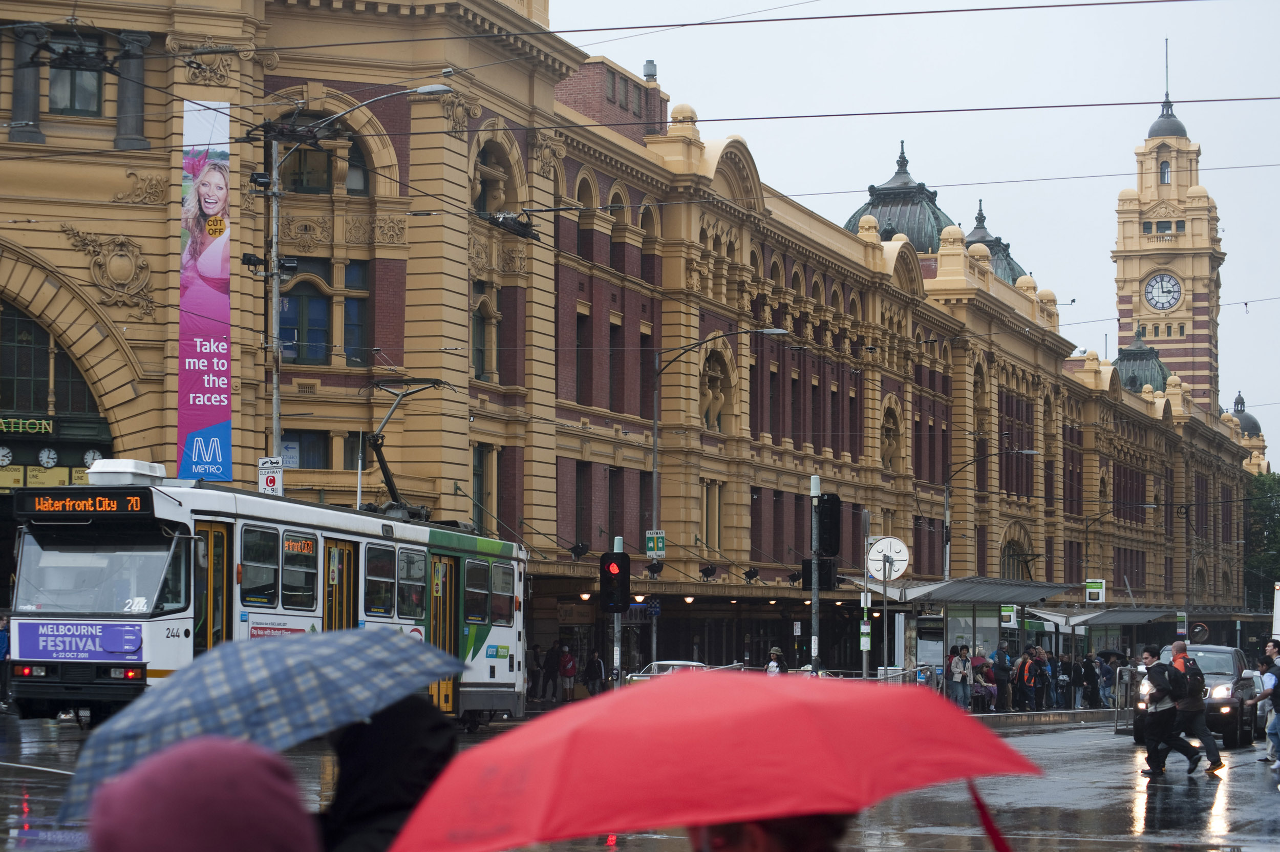 an image of A busy winter scene and umbrellas on Flinders street in Melbourne city, Australia.