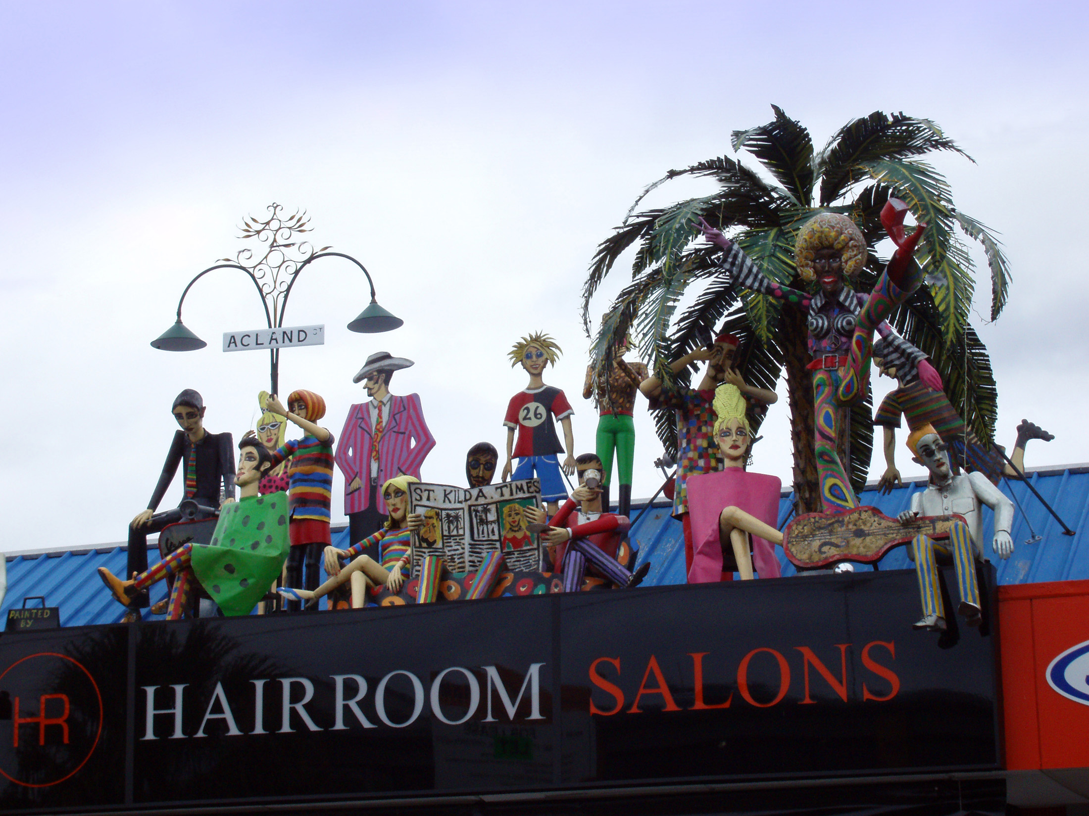 an image of Hairroom Salon Building Signage with Artistic Human Sculptures on Rooftop at St Kilda in Melbourne, Australia.