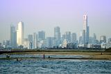 The distant Melbourne city skyline and CBD buildings from a beautiful, quiet suburban ocean beach.