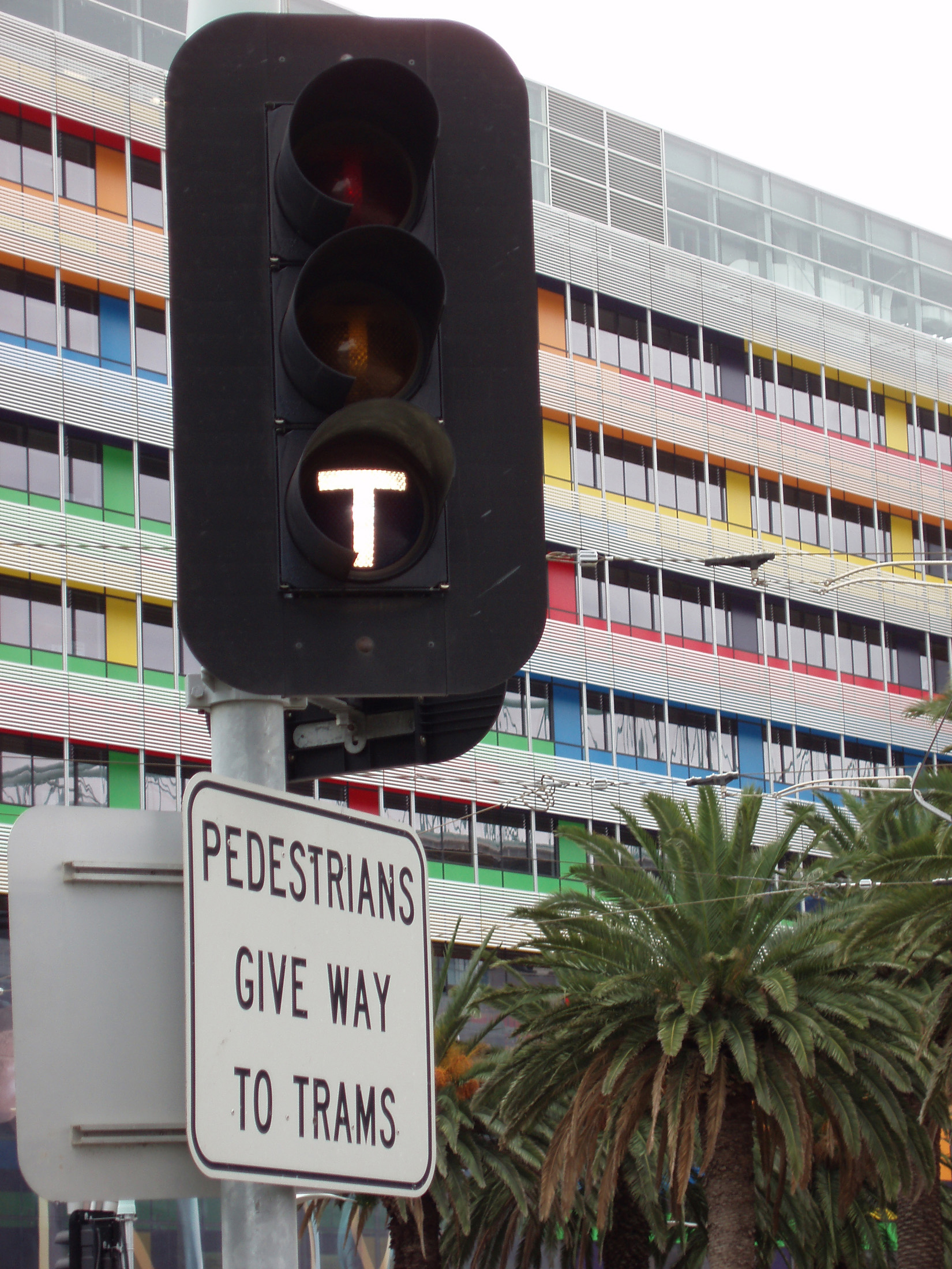 an image of Close up Traffic Light at Tramway in Melbourne Docklands with Colorful Modern Building at the Back.