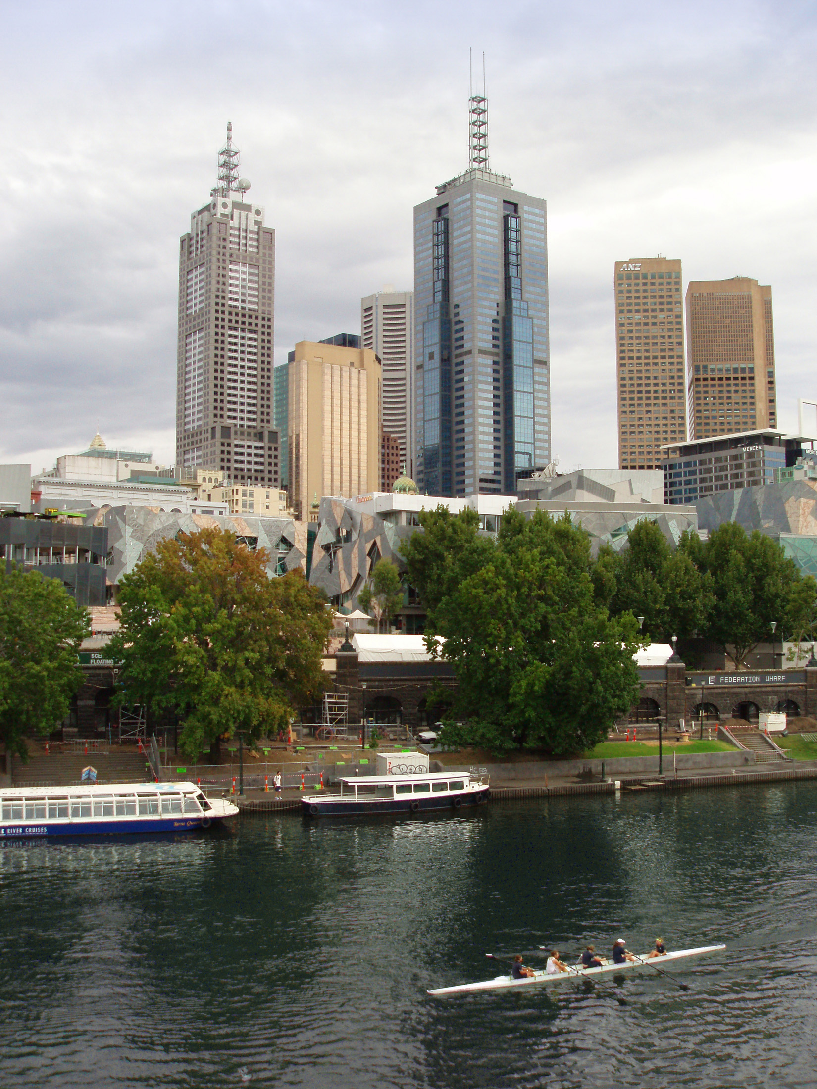 an image of High Rise Australian Buildings in Front Yarra River with Some people enjoying rowing. Located in Melbourne