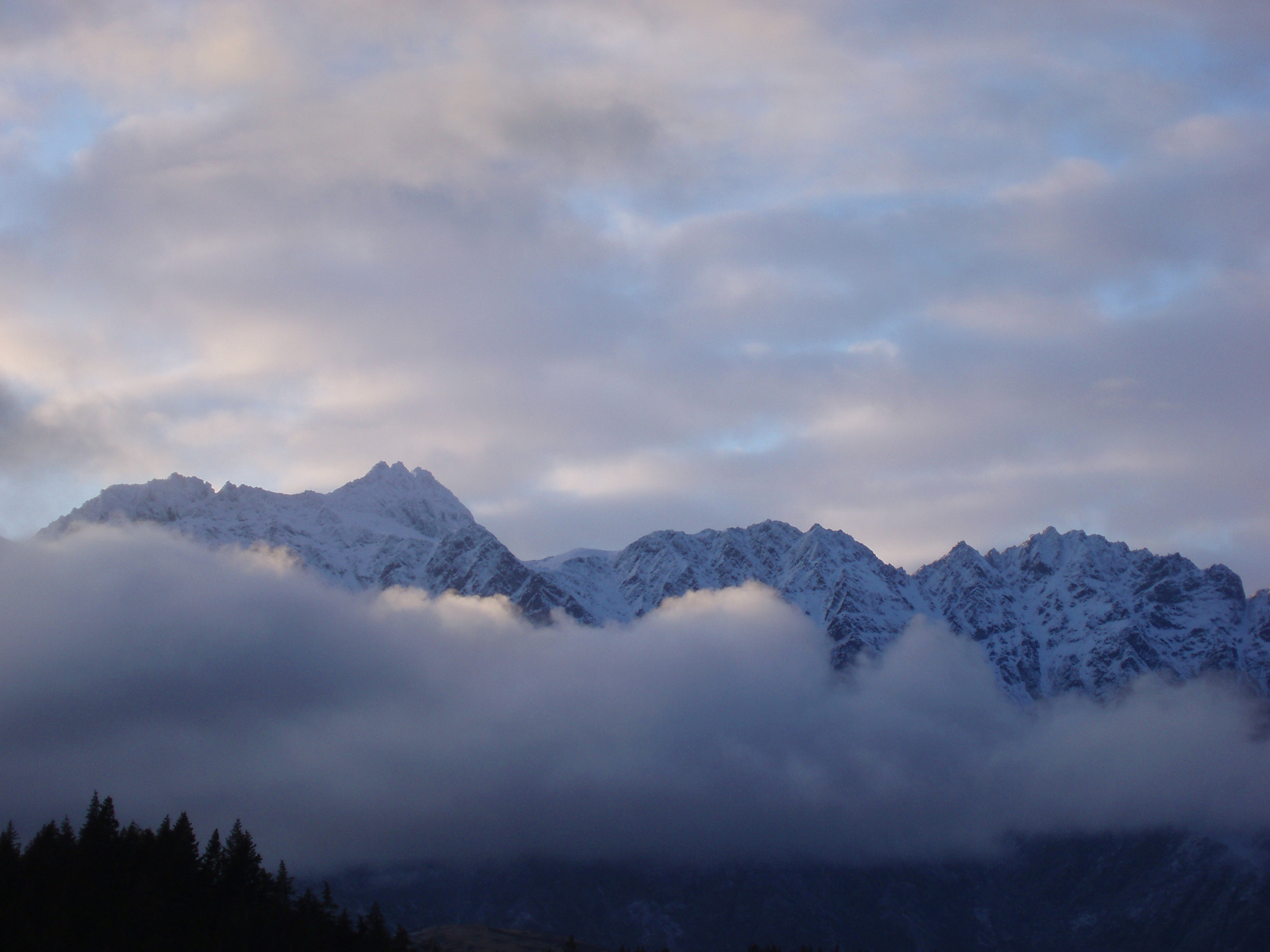 an image of clouded montain range, the remarkables as seen from queenstown, newzealand in winter