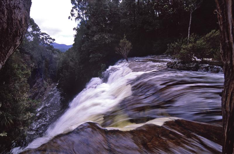 Fast flowing waterfall in Tasmania, Australia on the overland track with a close up view of the water cascading over a rock cliff to the river below
