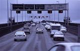 Traffic on a highway driving below a set of overhead road signs on the on the Tasman Bridge, Hobart, Tasmania