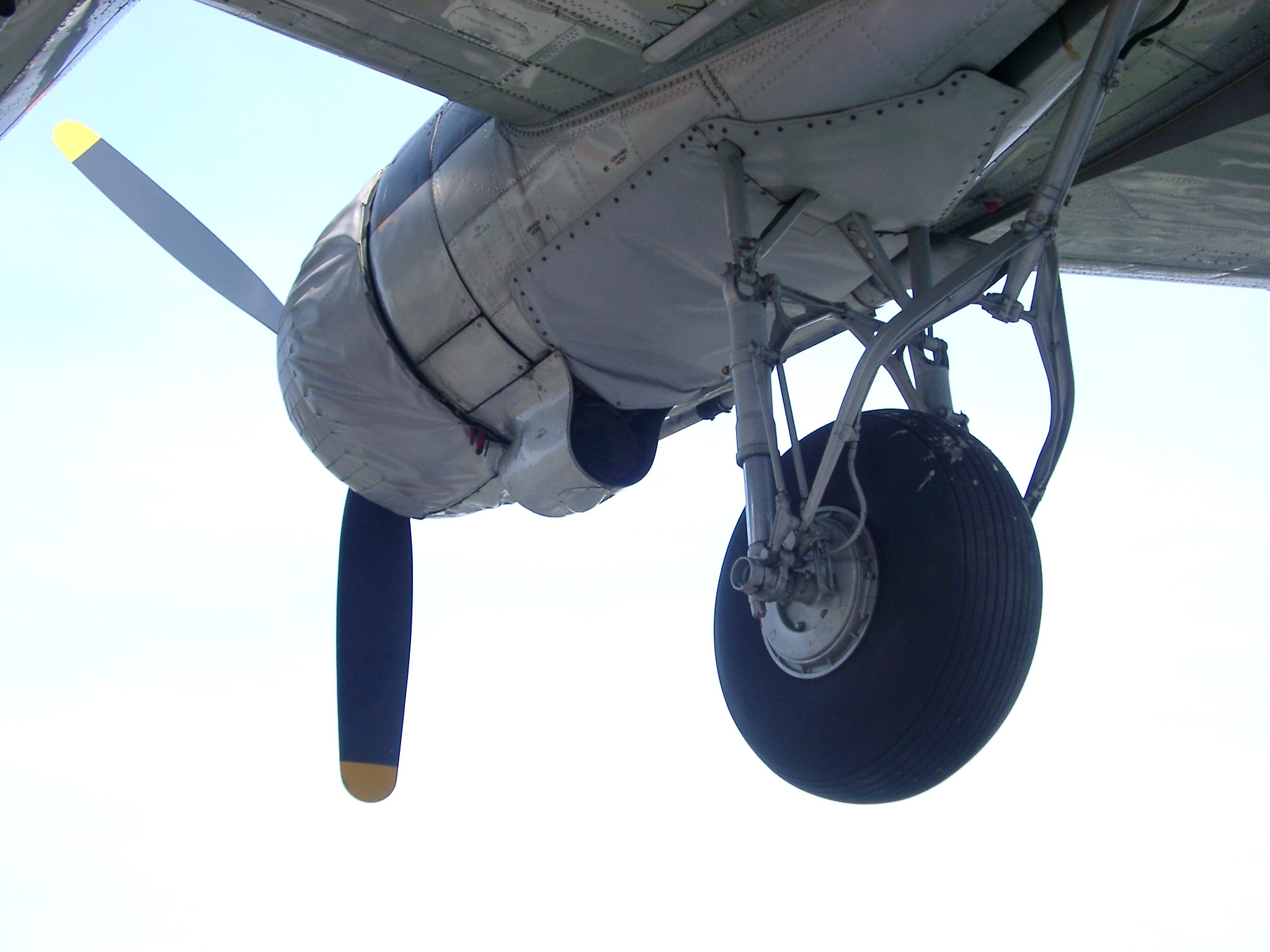 an image of Retro plane with a view from underneath of the propeller and a single landing wheel as it flies overhead
