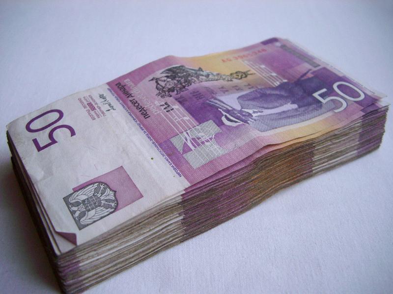 Wad of old Yugoslav cash in denominations of 50 stacked carefully on a white background