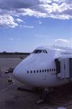 474 Jumbo aircraft loading for departure with a passenger skybridge attached to the side for embarkation as it stands on the apron at the airport
