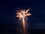 Colorful fireworks exploding in a night sky as a soaring rocket showers trails of fiery sparks in a festive pyrotechnic display at a celebration