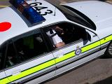 High angle close up view of police in a patrol car showing the number of the vehicle on the roof and sleeve of the police officer through the window