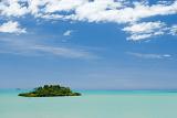 a tiny coral islet in crystal blue tropical waters