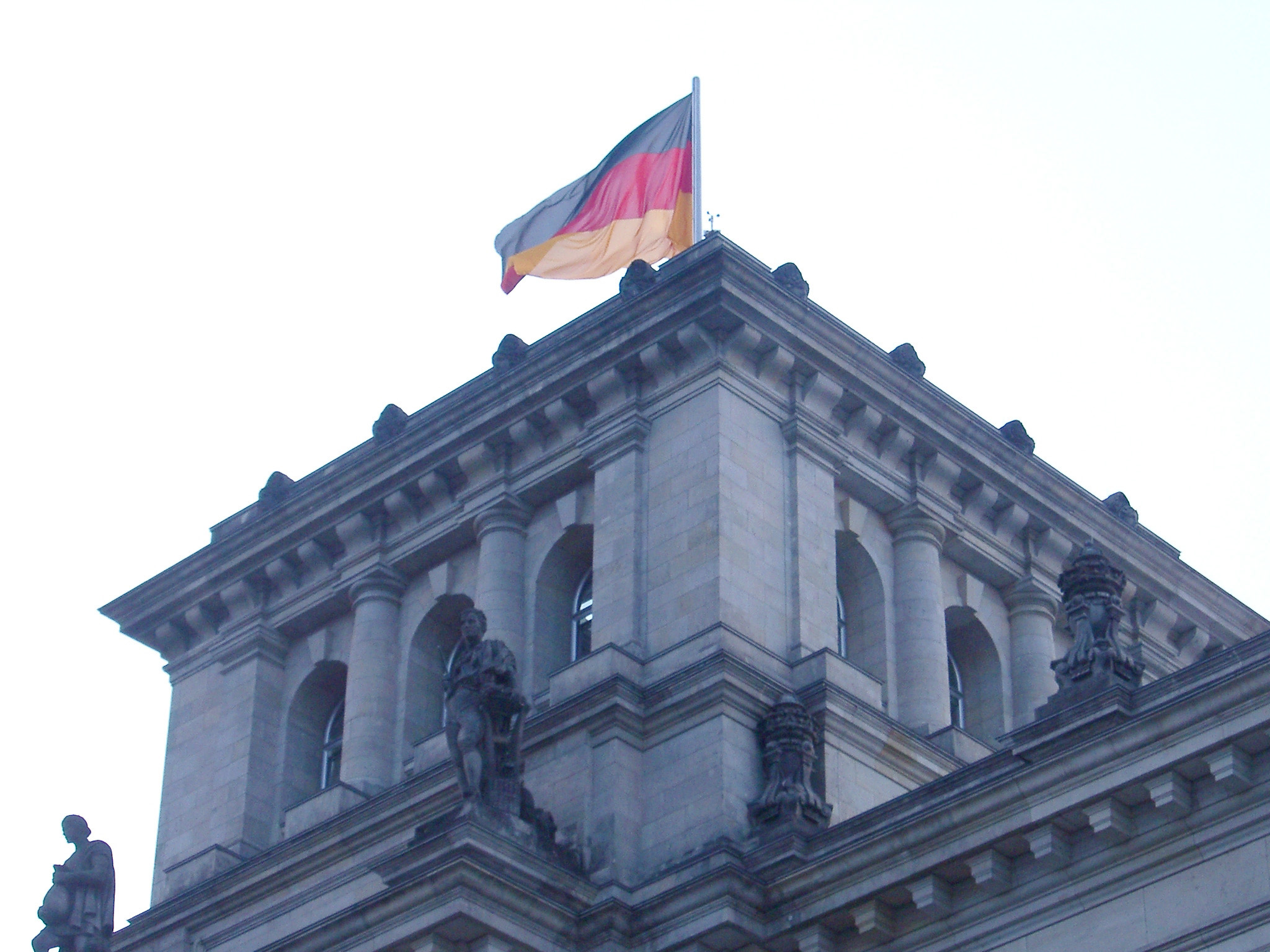 an image of German flag flying at the Reichstag Building, the seat of the government in Berlin, against a bright sky