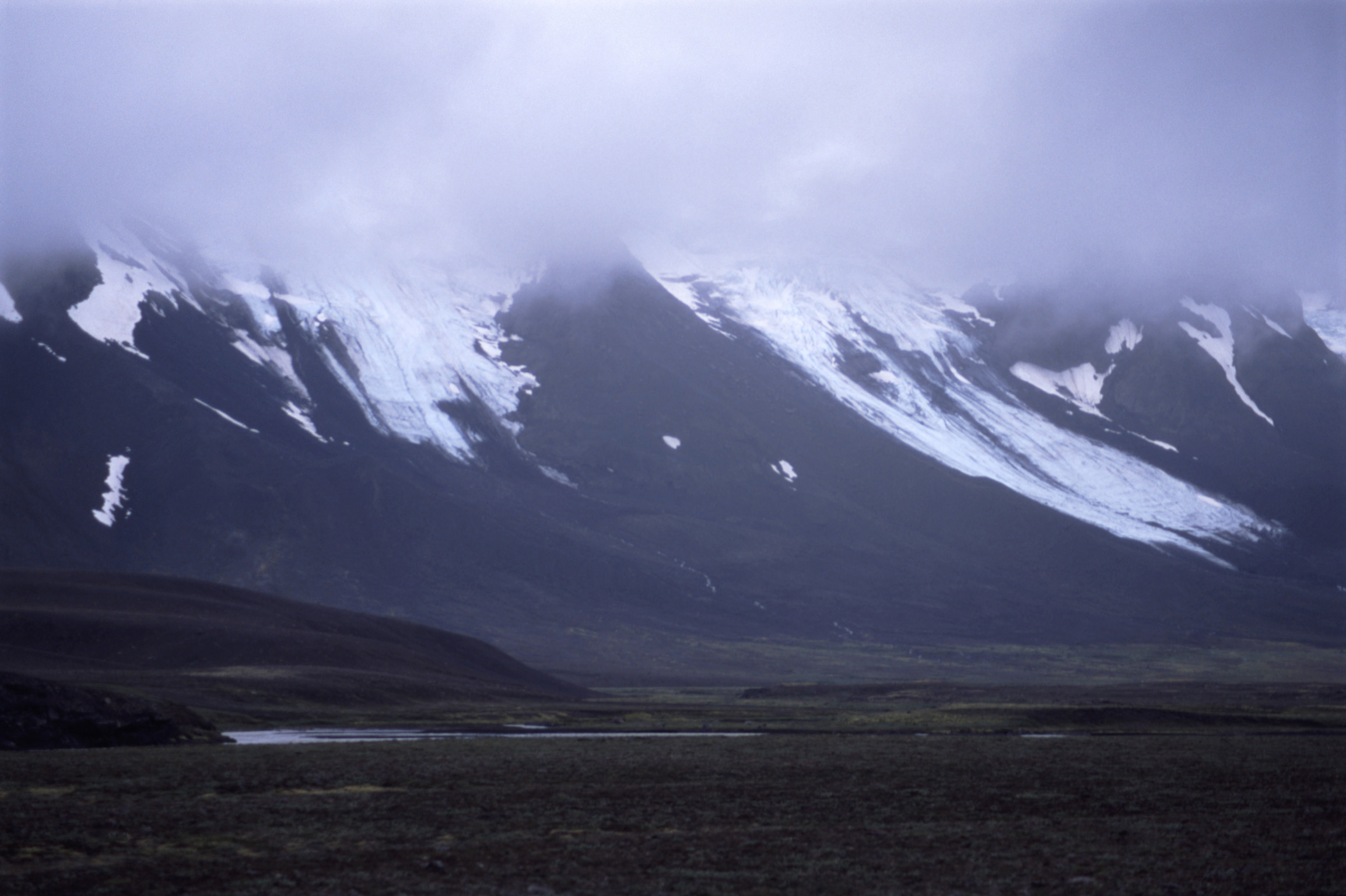 an image of Icelandic landscape with glaciers descending from high volcanic peaks shrouded in cloud and mist