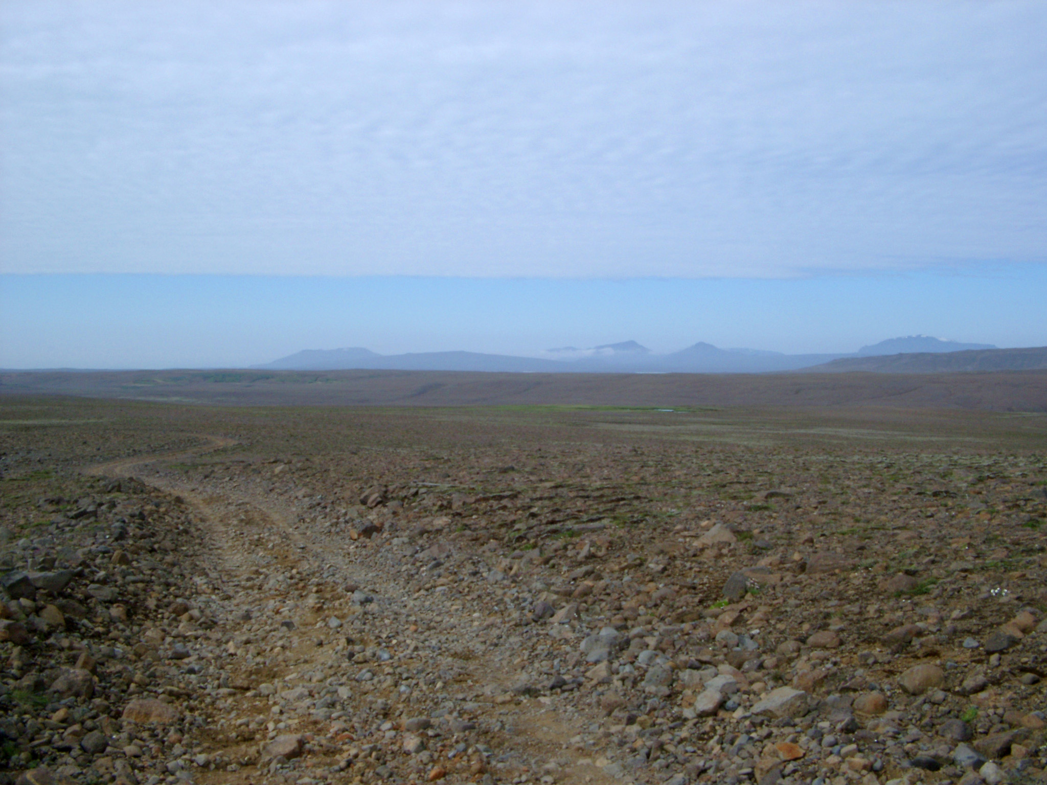 an image of Iceland Path on Wide Brown Field Isolated on Light Blue Sky Background.
