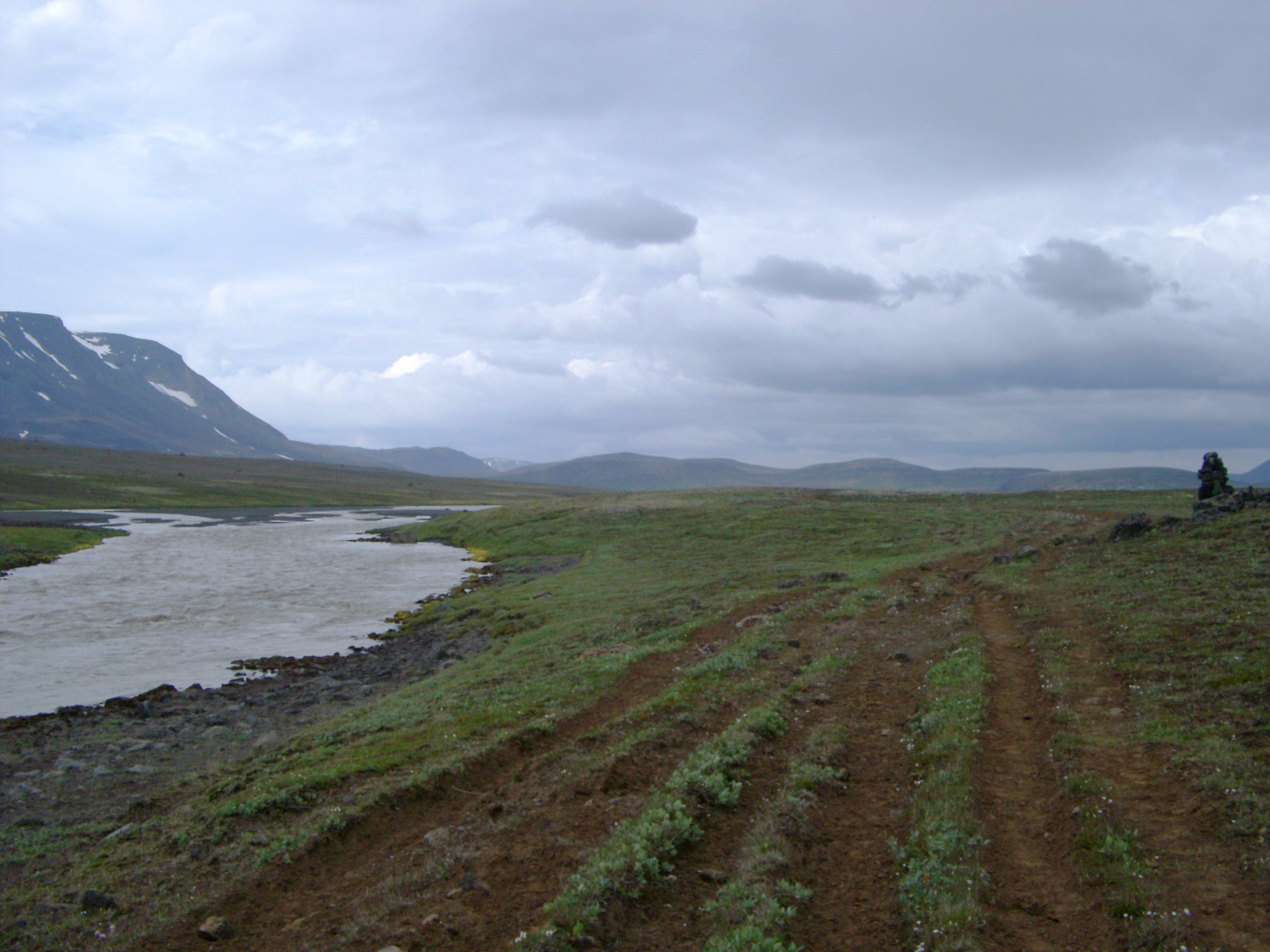 an image of a historic overland trade route in the highlands of icleand during summer, a stone cairn marks the route of the  path