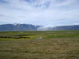 View over meltwater lakes and streams ringed with green grass to a distant volcanic mountain glacier in Iceland in a scenic landscape
