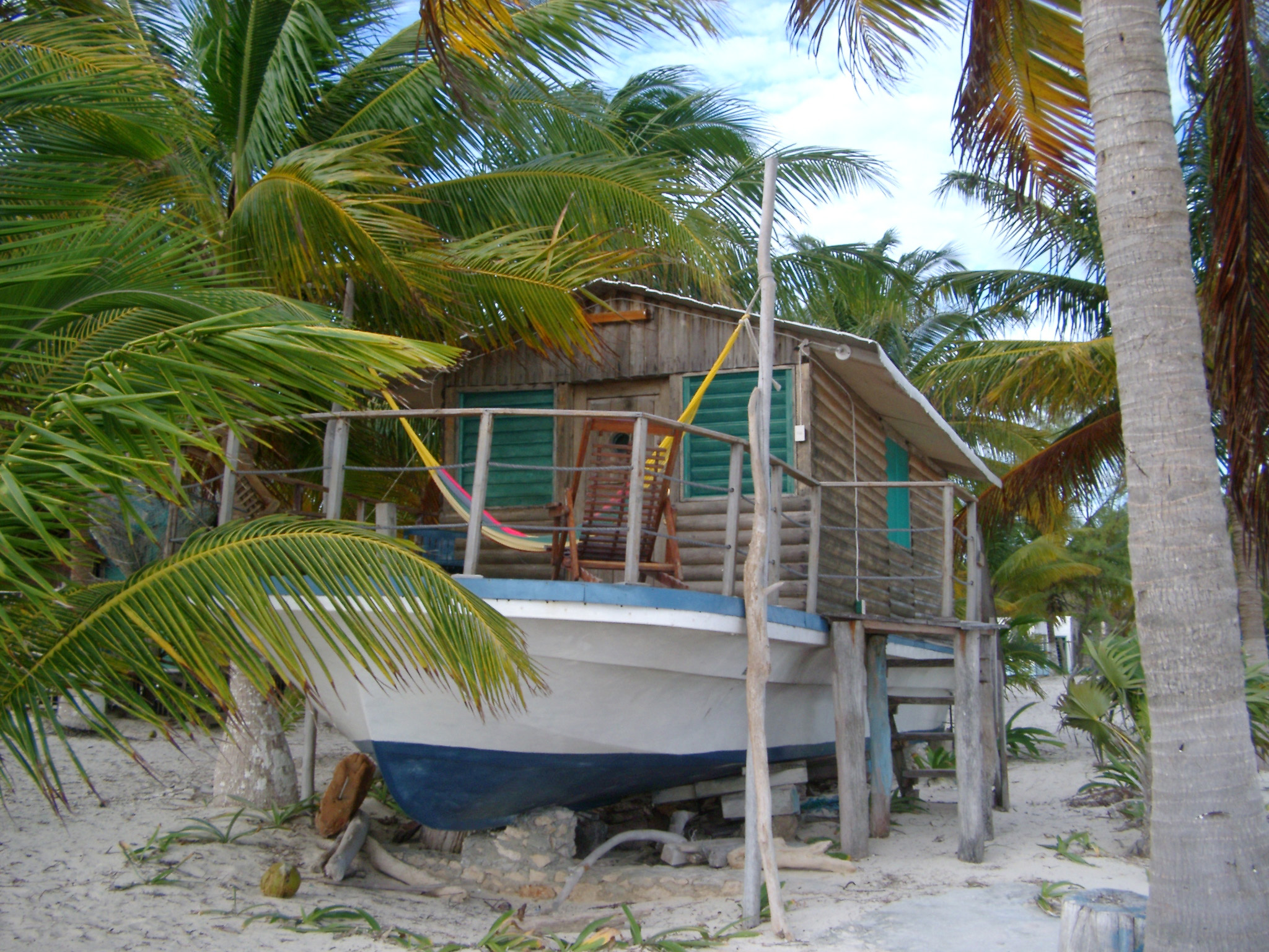 an image of Wooden log cabin houseboat in Mexico sited on the golden sand of a tropical beach amidst palm trees