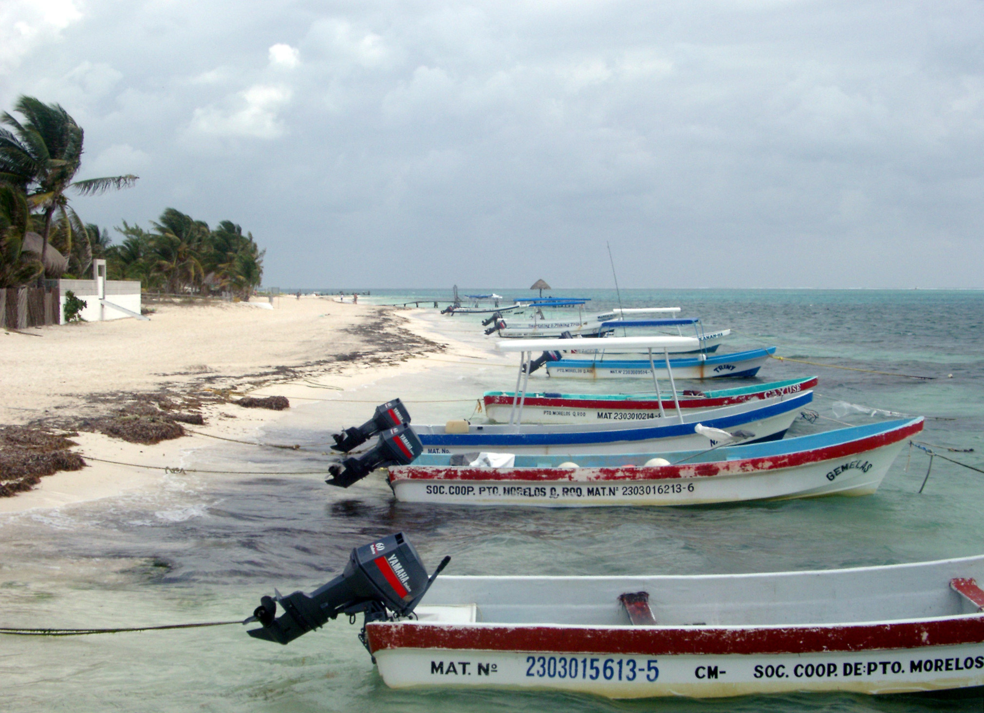 an image of Plenty Small Boats at beautiful Beach of Playa del Carmen Mexico. Isolated on Light Blue Gray Sky Background.