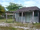 Small Old Vintage House on Grassy Landscape with Tin Sheet Wall. Located in Mexico