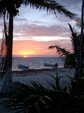 Boats and palms in a colorful Mexican sunset over a tranquil ocean and tropical beach