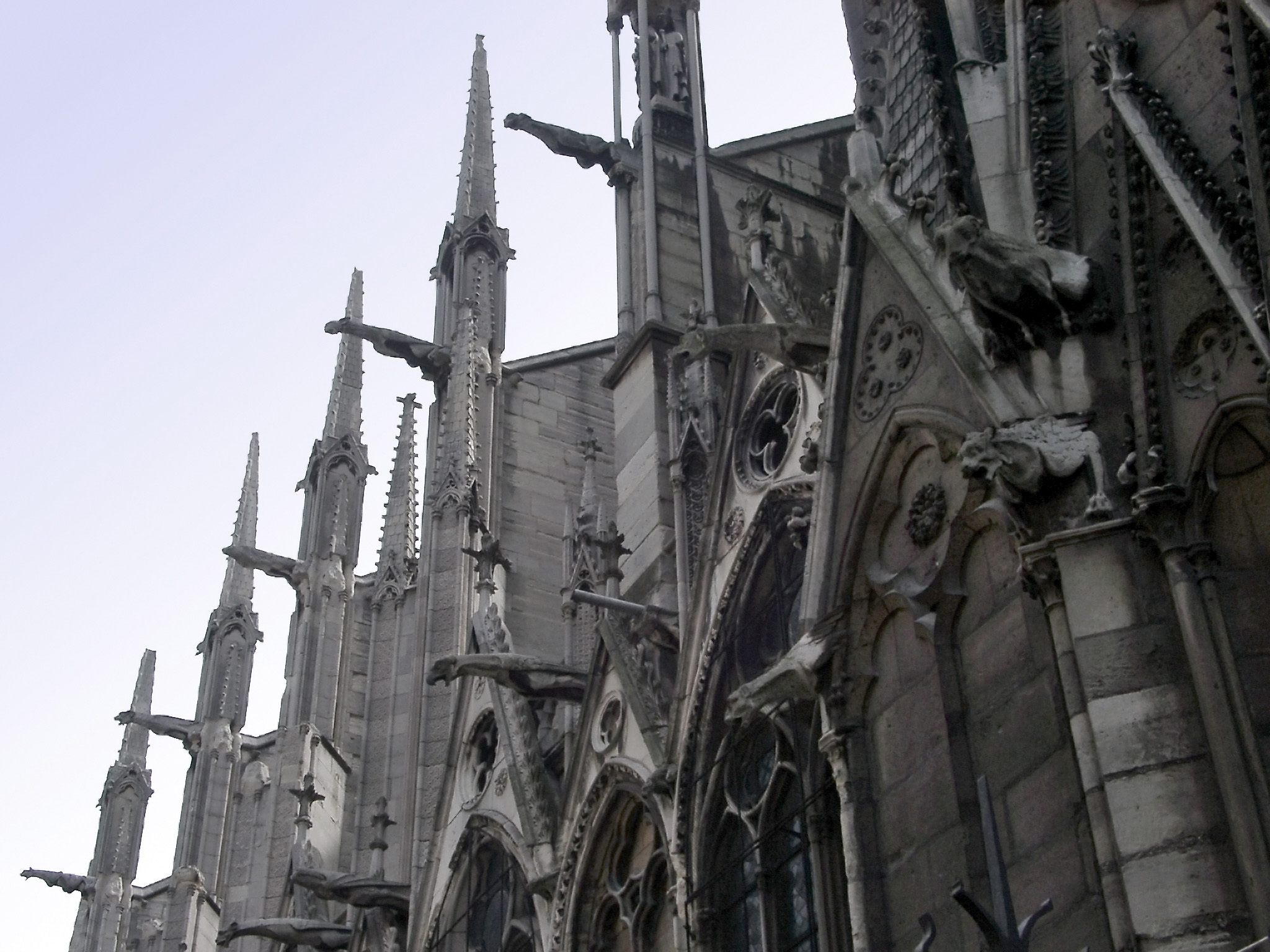 an image of Notre Dame cathedral, Paris showing the delicate spires on the flying butresses and gargoyles along the side of the exterior of the building