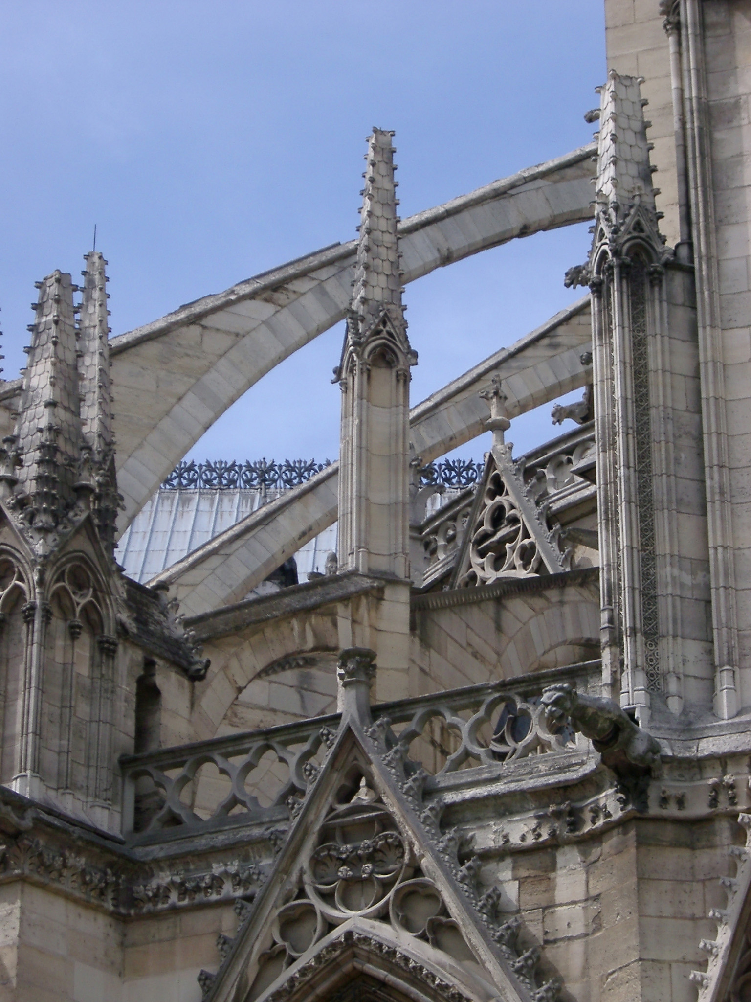 an image of Notre Dame Cathedral flying buttress detail showing the arched masonry support directing the thrust from the roof away from a main structure to an outer buttress
