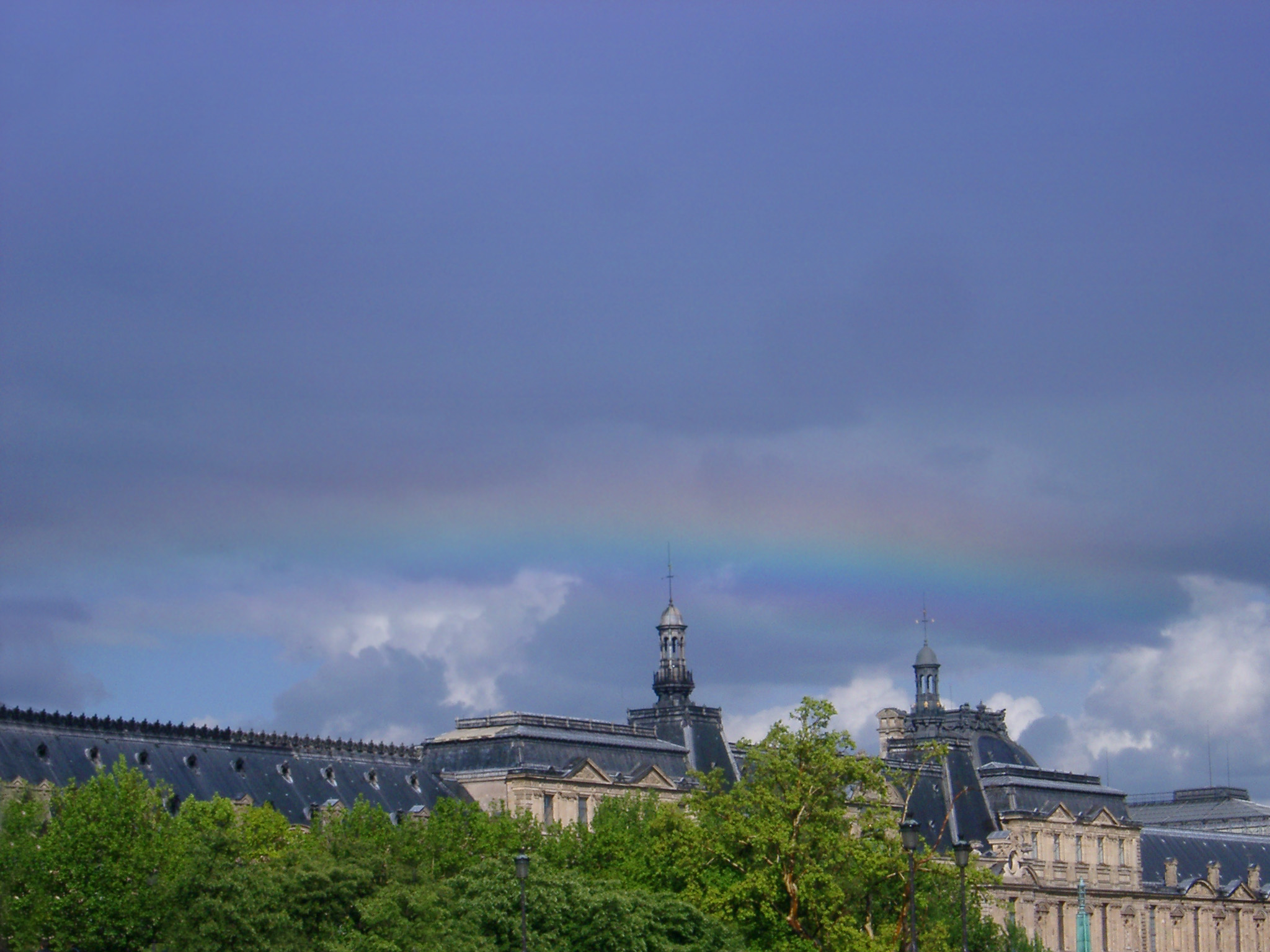 an image of Rainbow over Louvre Museum Rooftop in Paris,France