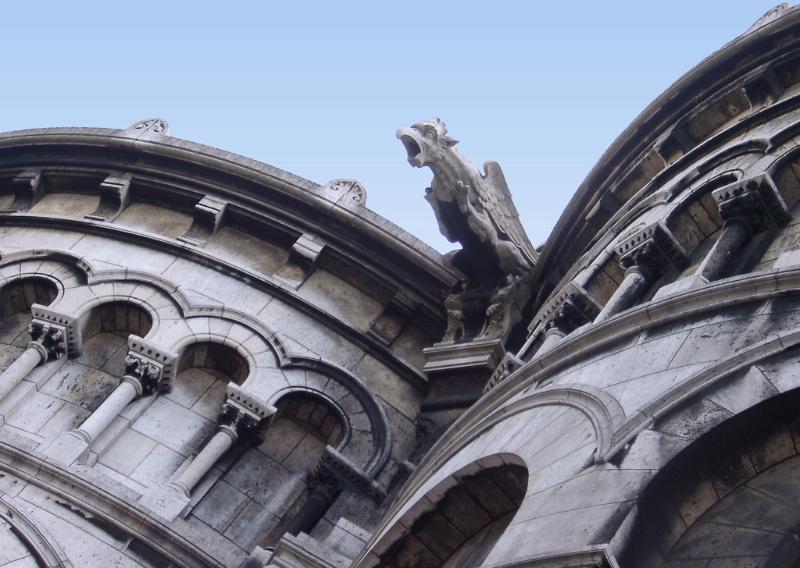 Old Vintage Gargoyle Sculpture on the roof of sacre coeur, Isolated on Light Blue Sky Background.