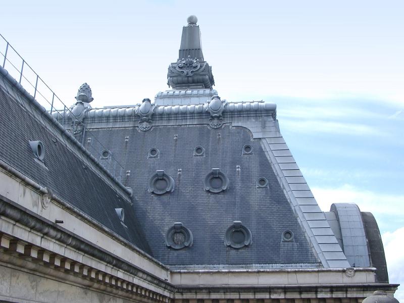 Paris roof details on a townhouse showing round attic windows and hooks for roofing work in the exterior of the tiles