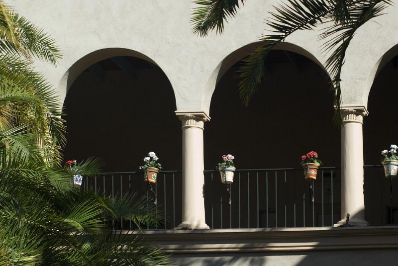 Arched facade decorated with flower pots and tropical palms in Balboa Park, an urban cultural park in San Diego, California,