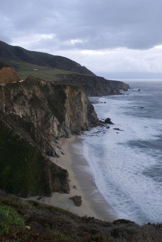 Beautiful Big Sur Coast Seascape with Cool Sea and Grassy High Hill, Isolated on Lighter Blue Gray Sky Background. Captured in Aerial View.