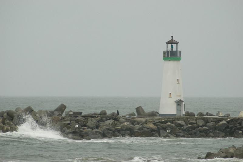 Lighthouse at Rocky Monterey Bay End Located at Santa Cruz Harbor. Isolated on Foggy Sky Background.