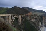 Scenic view of the steep rocky cliffs on the Big Sur coastline in Californa with the concrete arch of the Bixby Creek road bridge