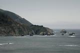 Big Sur coast, California on a grey overcast rainy day with a rocky headland jutting out into a calm ocean