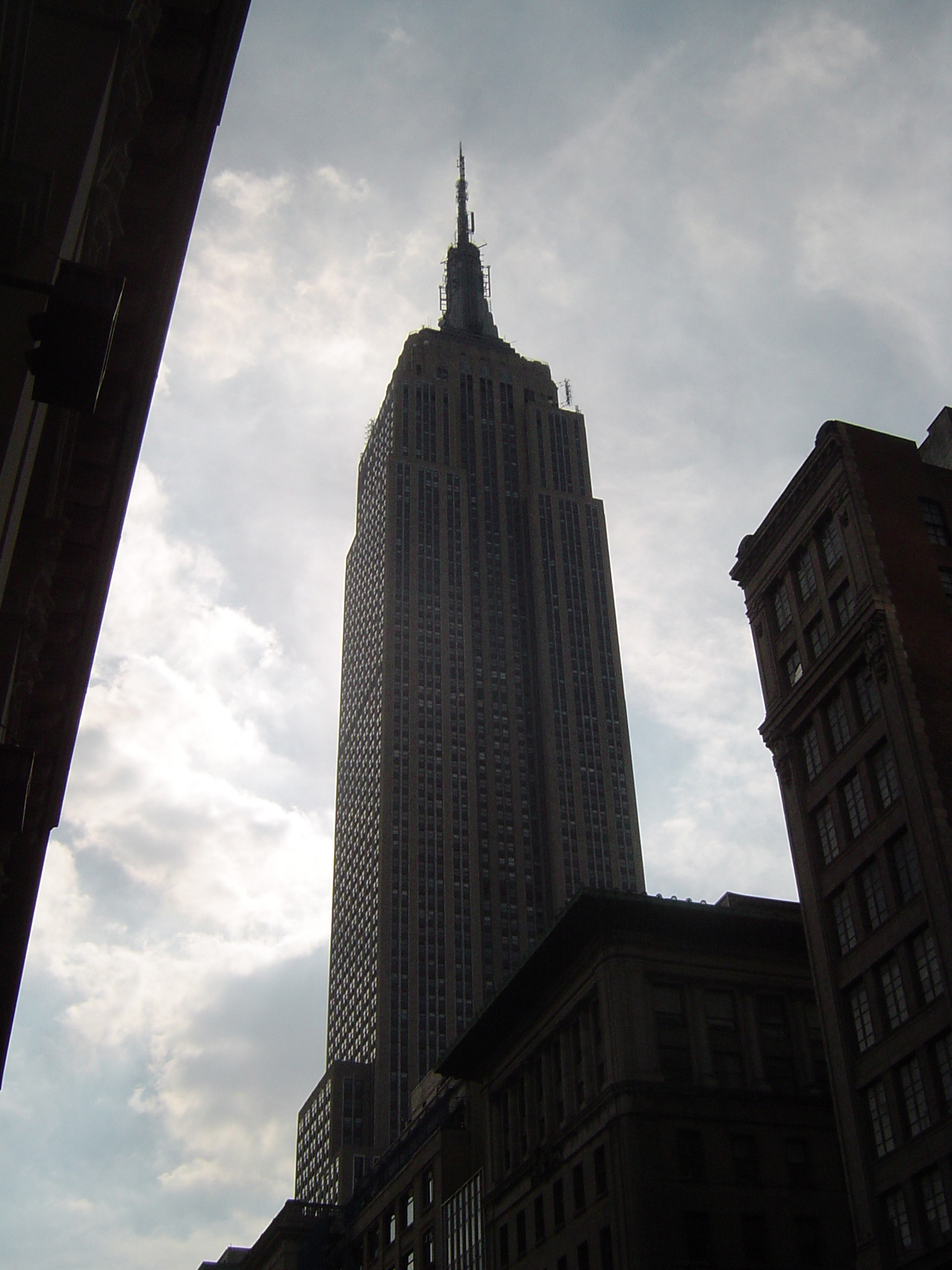 an image of Low angle view looking up of the Empire State Building, Manhattan, New York, silhouetted against a cloudy sky