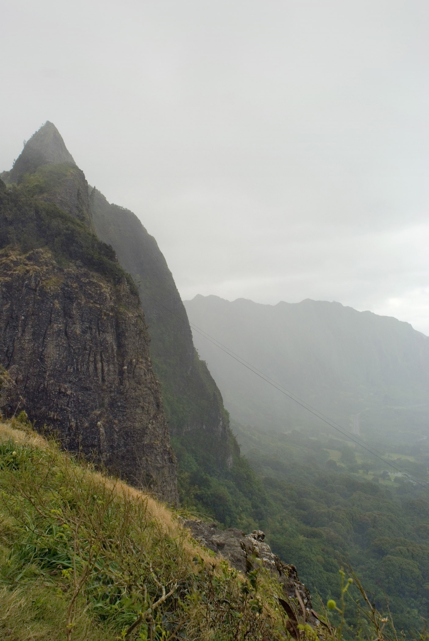 an image of View from the Pali Lookout in Ohau, Hawaaii looking out over the mountain ranges on a rainy misty atmospheric day
