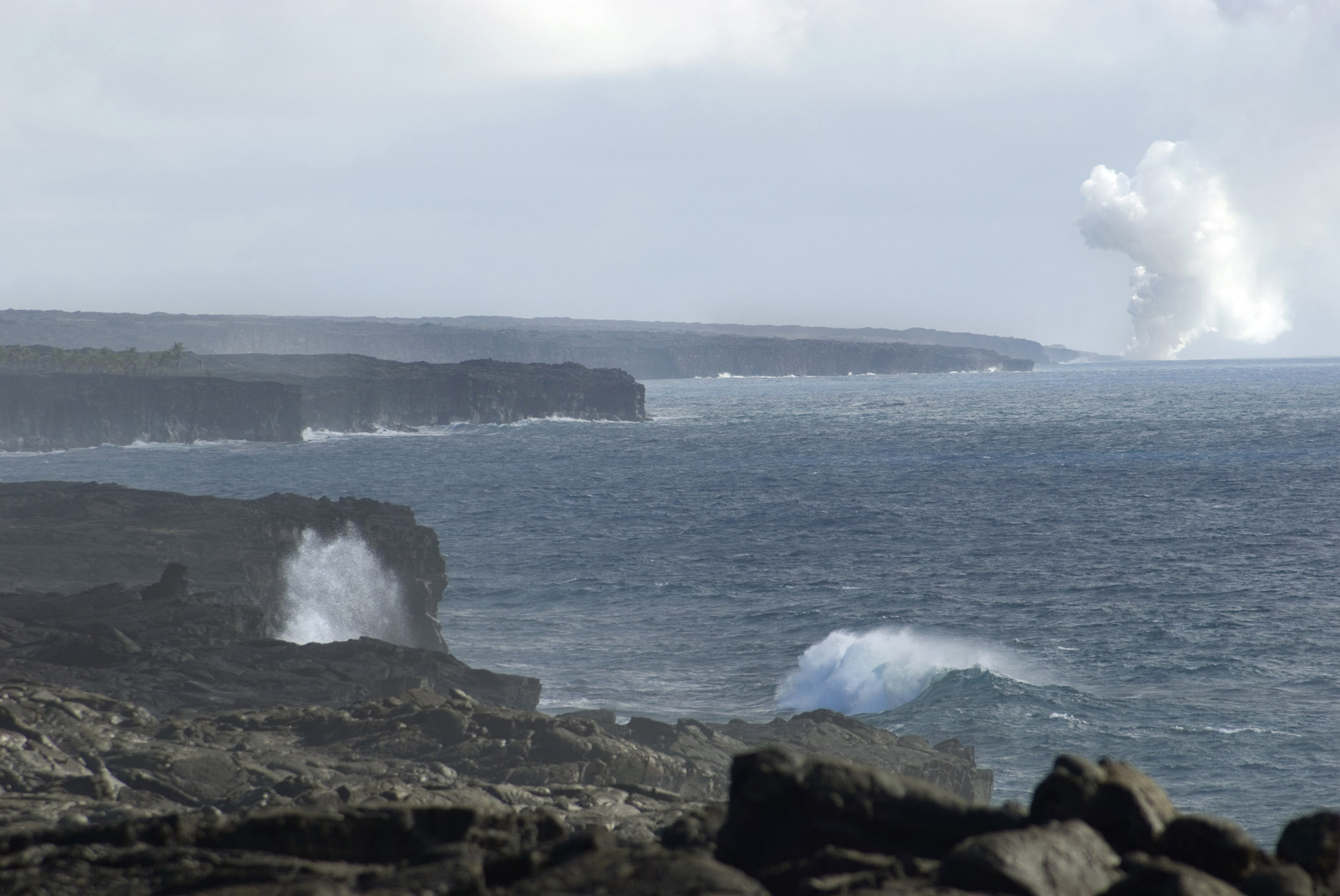 an image of When Lava Meets the Ocean with a plume of steam rising in the distance