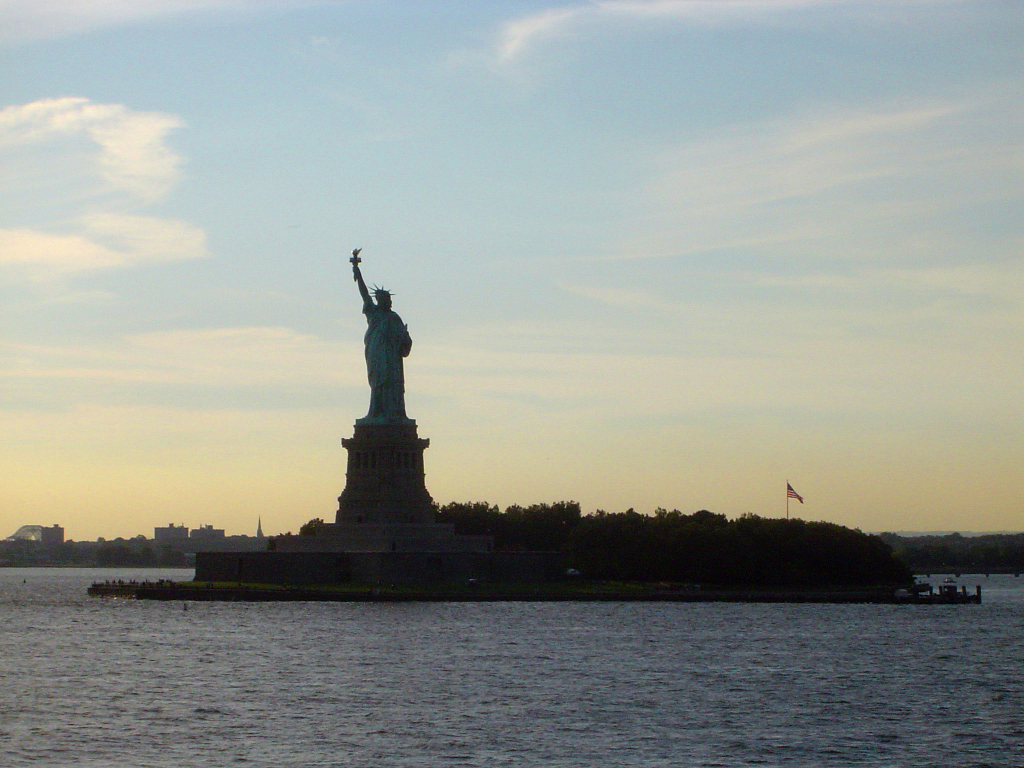 an image of Statue of Liberty, New York , USA, at dusk silhouetted against a colorful evening sky viewed over the water