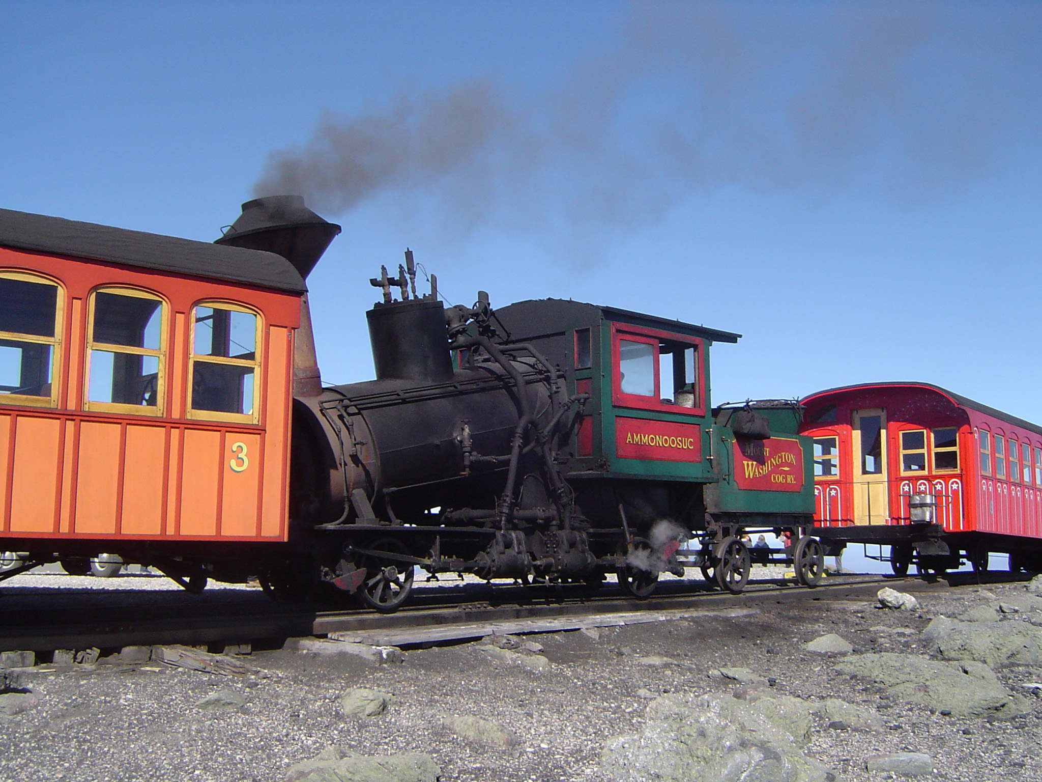an image of Close up Running Vintage Steam Locomotive on Cog Railway. Captured on Gradient Light Blue Sky Background.