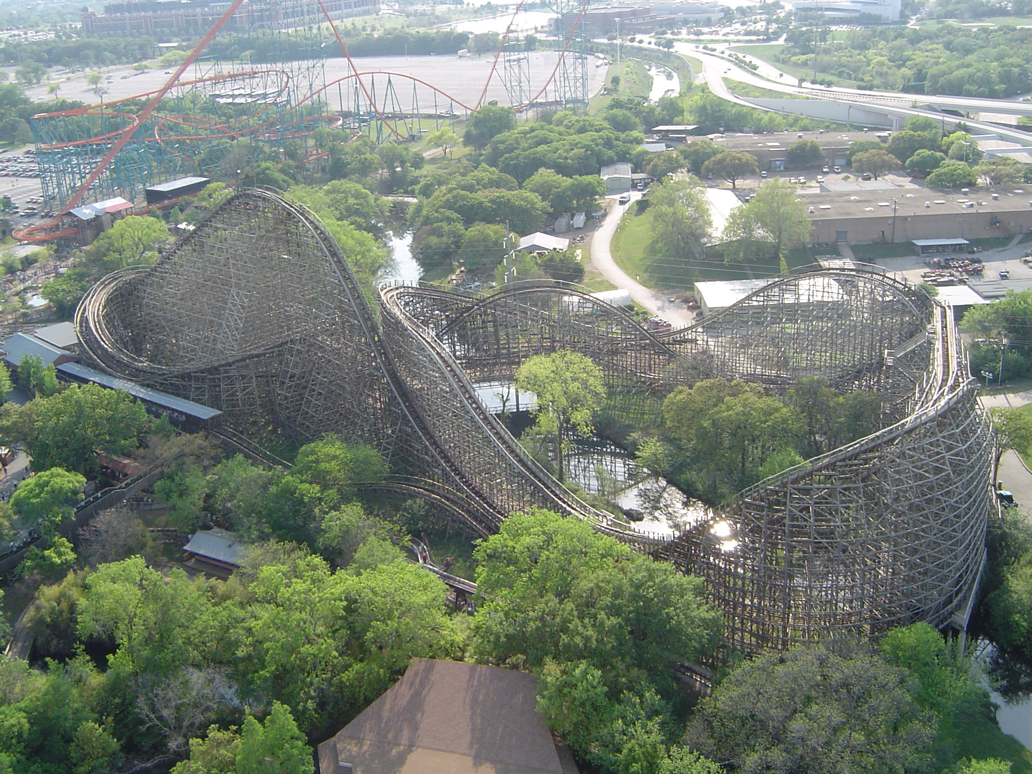 an image of Aerial view of a roller coaster ride in a theme park in the USA set amongst leafy green trees for that ultimate thrill